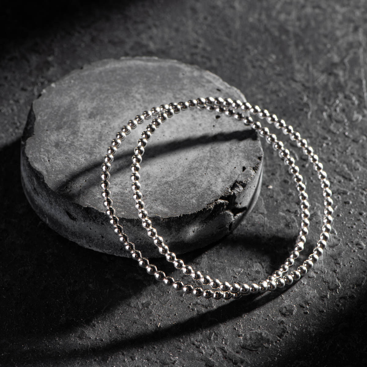 Handmade silver bangles stacked on a grey stone