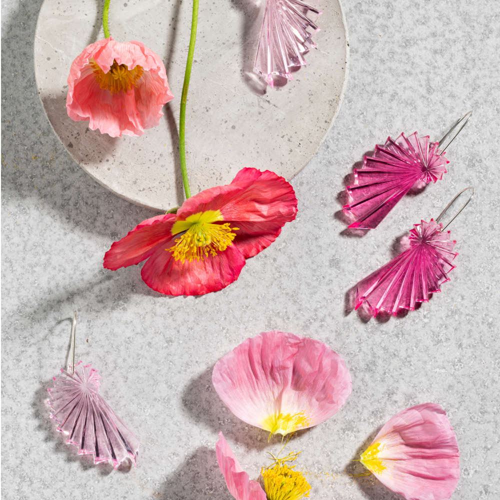 Pink flowers and pink earrings are arranged in a flatlay